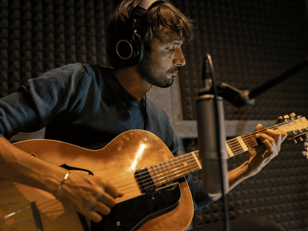 Musician recording acoustic guitar with the best recording microphone