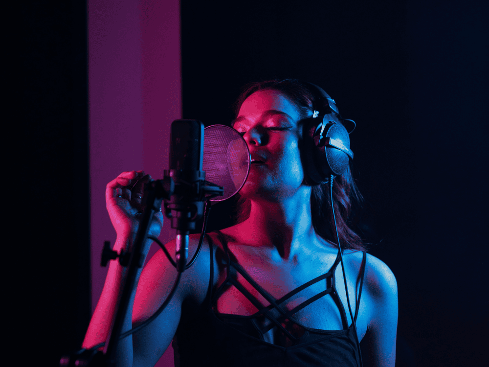 Female singer recording vocals in studio using a USB/XLR singing microphone