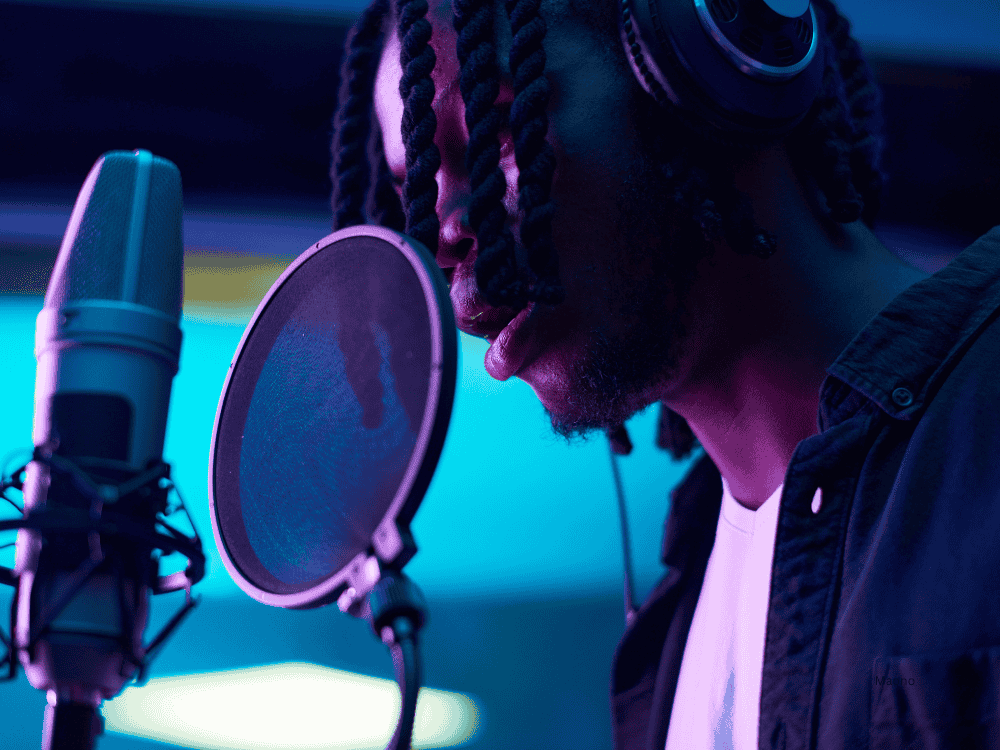 a male musician recording in a studio using a microphone for singing