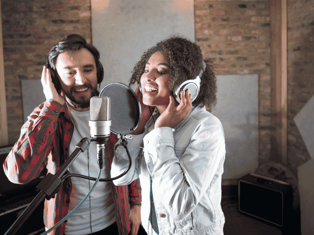 A male an female vocalist using a USB singing microphone for voice recording 