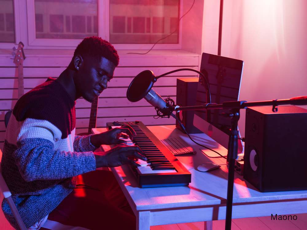 a male playing with keyboards and producing music using a recording microphone