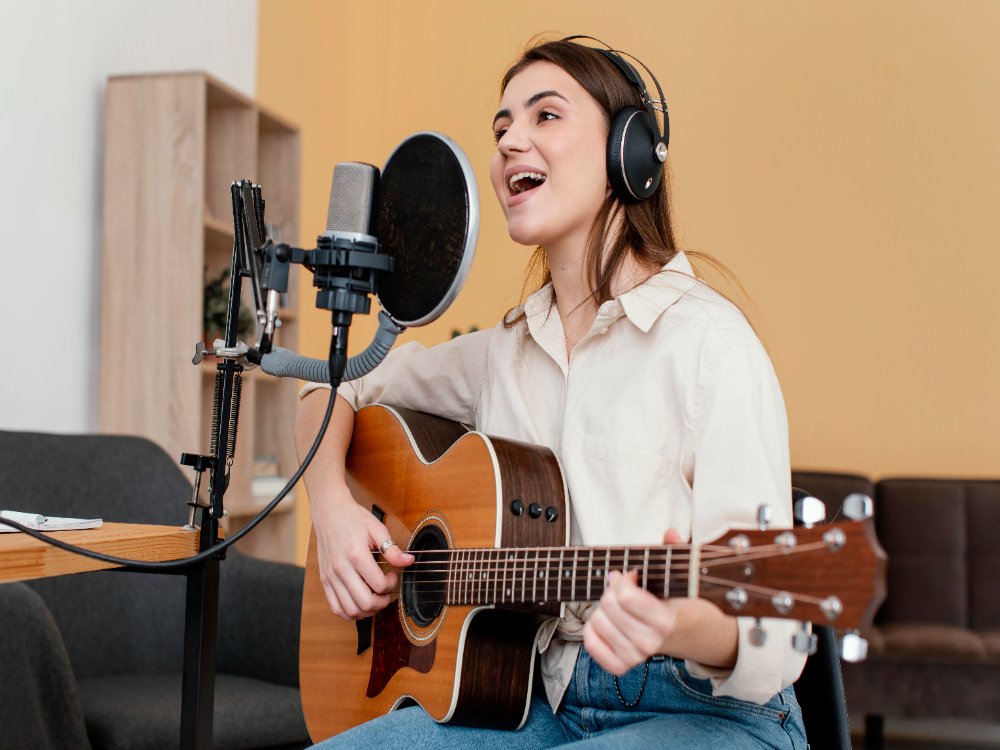 female singing and playing guitar in a studio