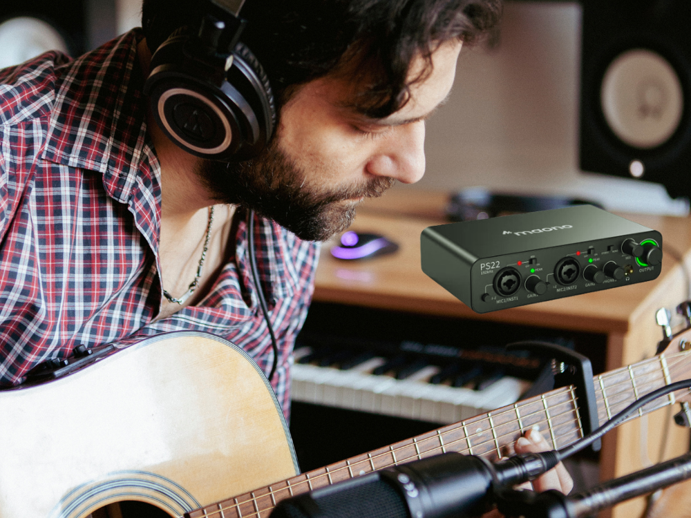 male recording music with guitar and audio interface