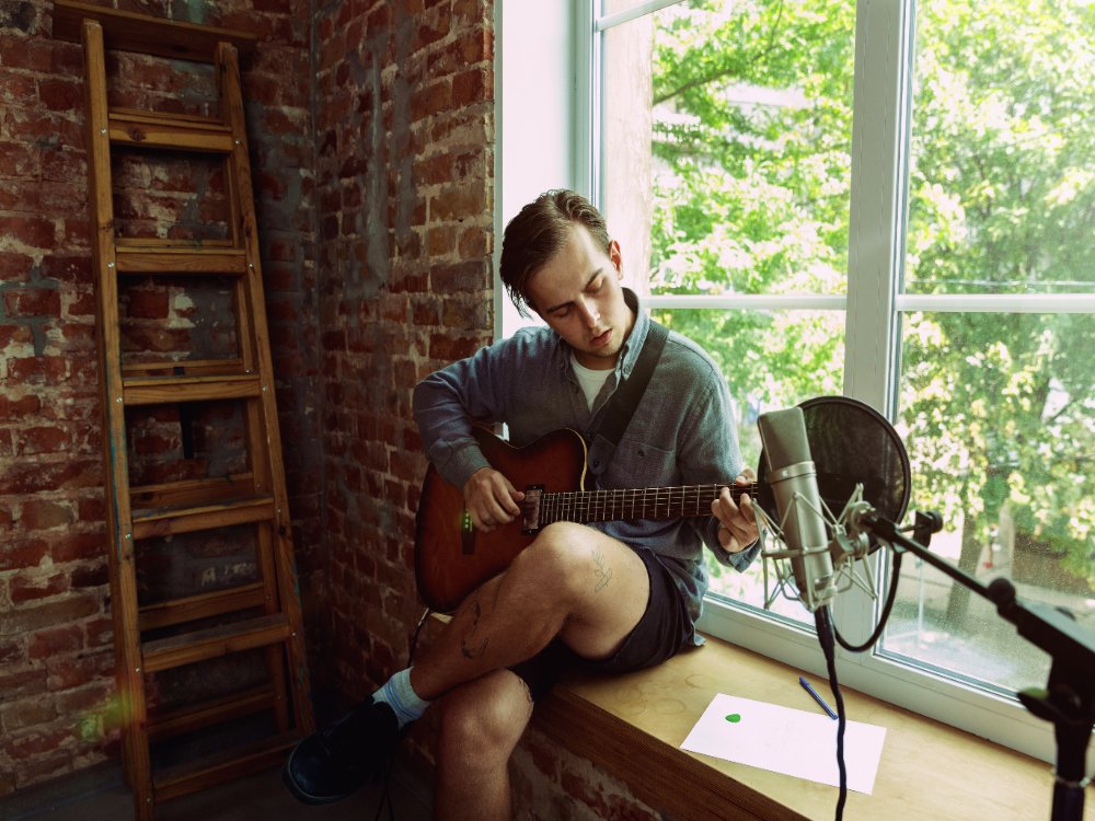 a man recording music with guitar and microphone image by Freepik