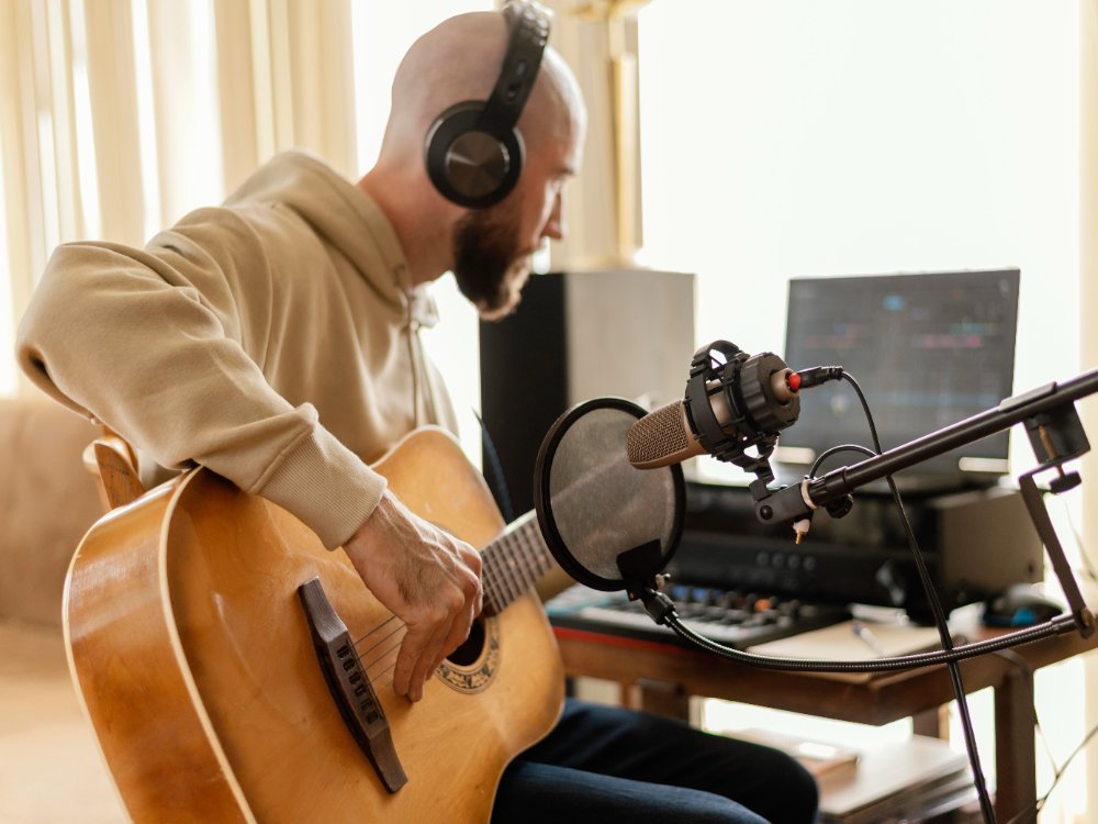 male playing the guitar and recording